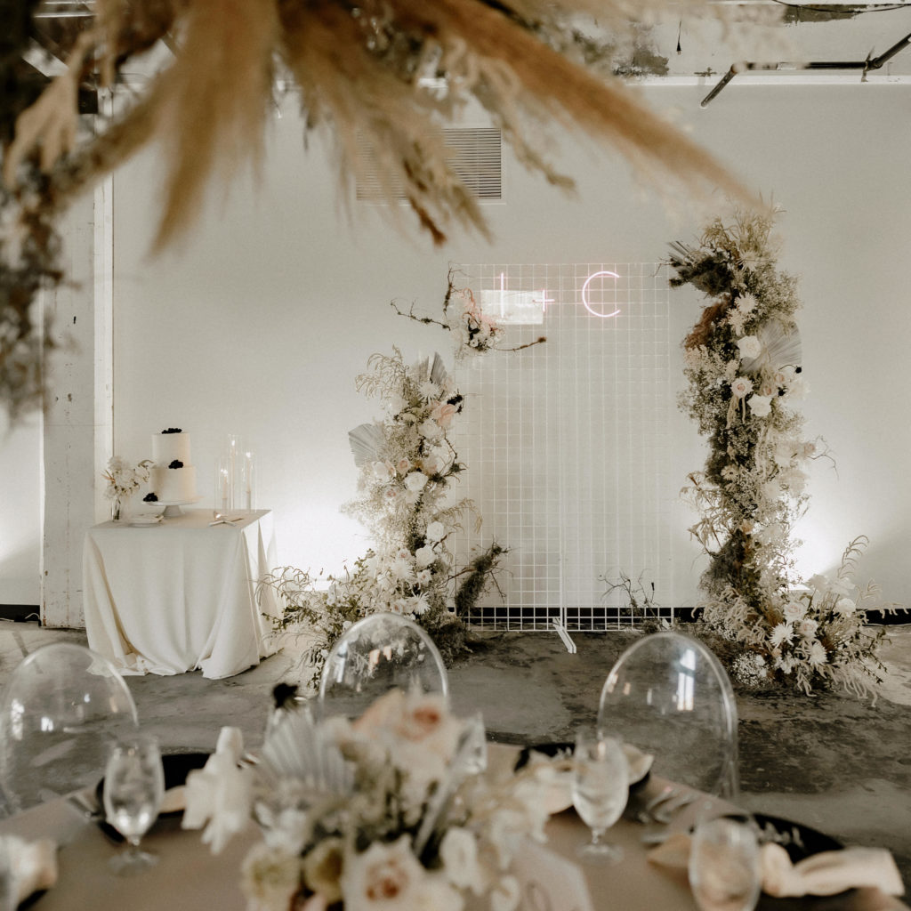 stunning industrial chic wedding with dried floral installations, ghost chairs, and neon sign