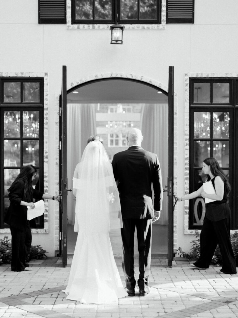 A bride and her father prepare to walk down the aisle at The Peach Orchard in Spring Texas. The Chancey Charm team of coordinators mans the doors. 