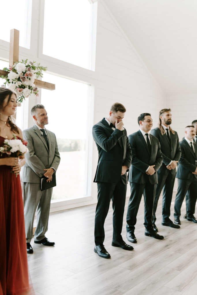 An emotional groom wipes tears from his eyes during his wedding ceremony at The Farmhouse Events. 