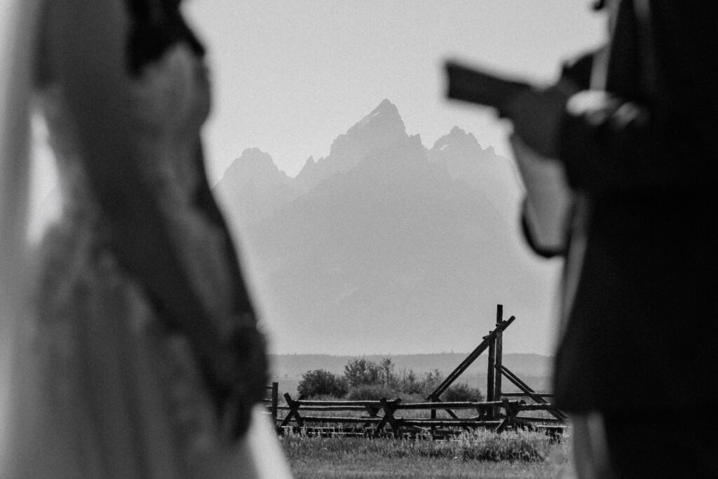 In the foreground a blurred couple exchange wedding vows. In the background Grand Teton reaches into the sky.